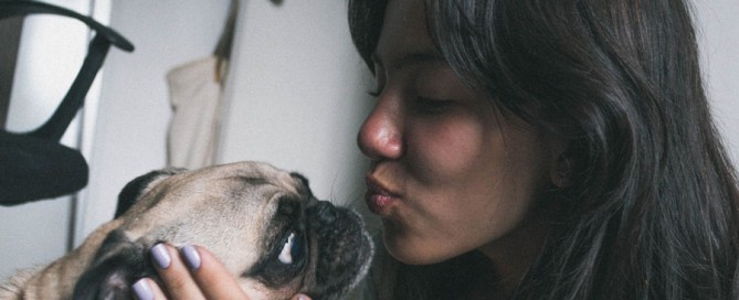 woman kissing a pug