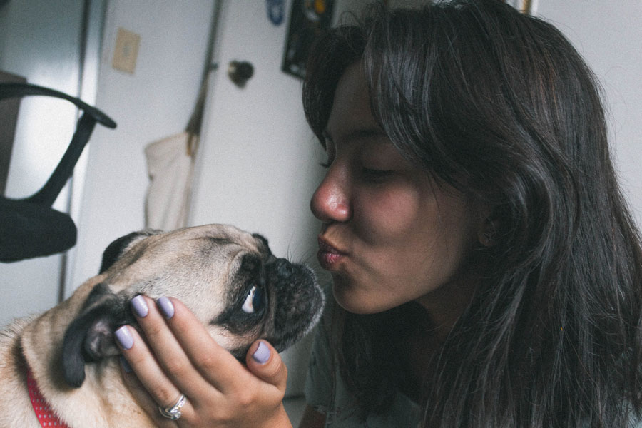 woman kissing a pug