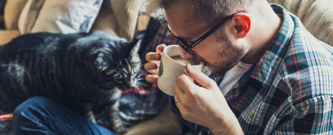 man sat on sofa with cat, pet sitting