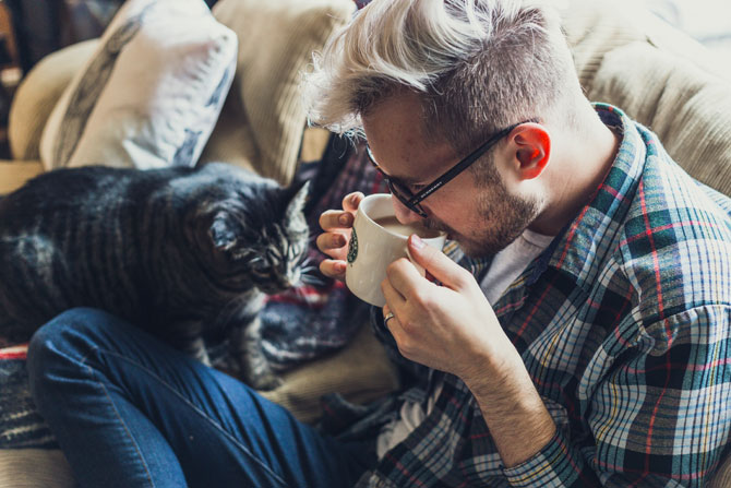 man sat on sofa with cat, pet sitting